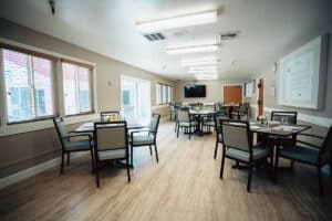 Dining room with tables set including flowers in vases and a flat screen TV on the wall.