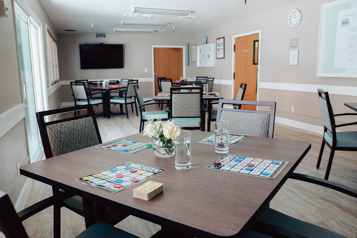 Dining room set up for activities with bingo and playing cards on tables.