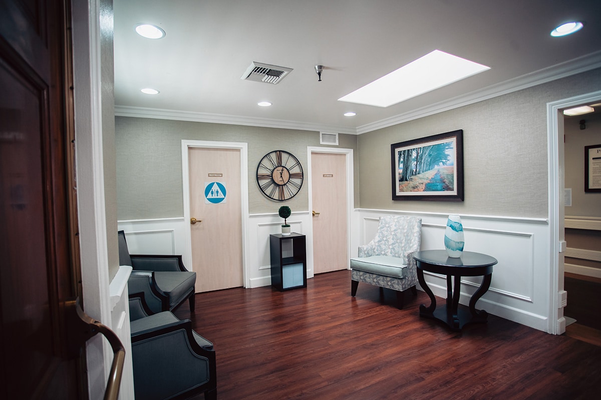Del Rosa lobby with teal club chairs, hardwood floors and large clock and painting on the wall.