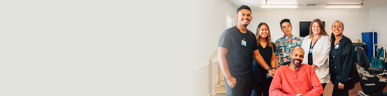 several rehab therapists standing with a resident in a wheelchair in the rehab gym at Del Rosa Villa Nursing Center
